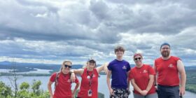 Five staff members from the Boys and girls clubs of central and northern new hampshire stand on top of a mountain in New Hampshire. They are smiling and enjoying beautiful scenery and nature.